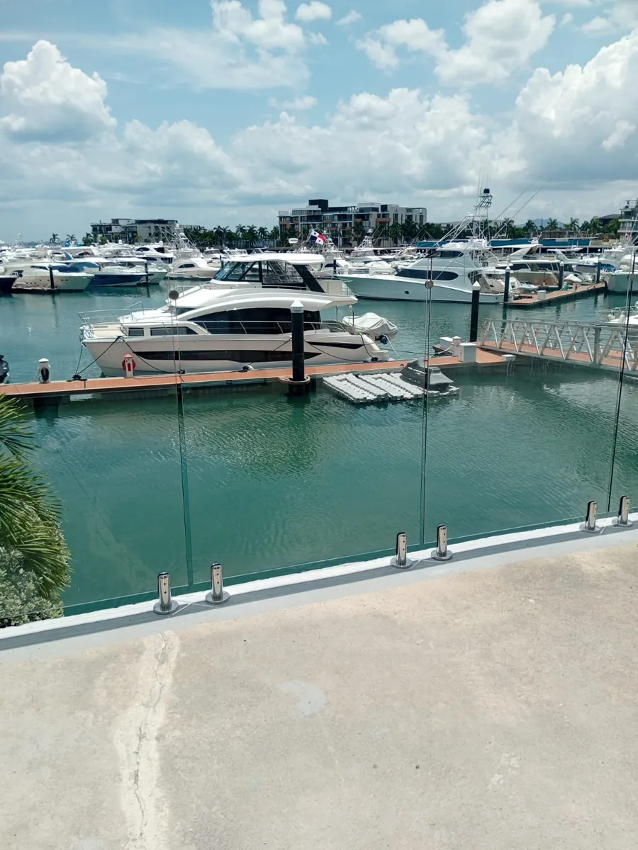 Baranda de vidrio templado con soportes de acero inoxidable frente a una marina